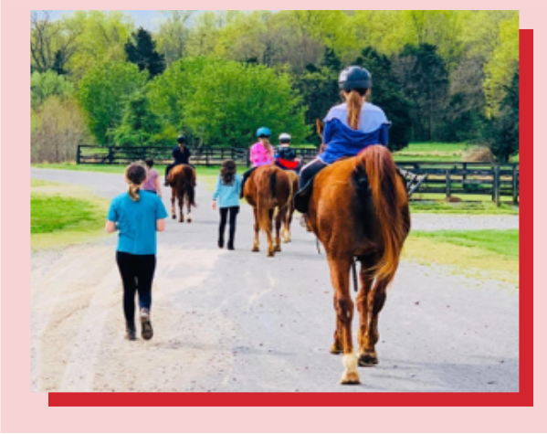 A group of people riding horses down the road.